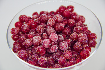 frozen red currants in a glass plate on a white background