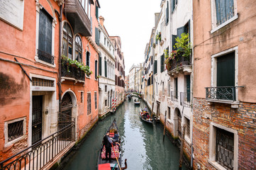 Fototapeta na wymiar 09.10.2019 Venice, Italy, gondola with tourists floating on a narrow channel with turquoise water. The historic center of the city, Windows with wooden shutters.