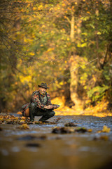 Handsome fly fisherman working the line and the fishing rod while fly fishing on a splendid mountain river for rainbow trout