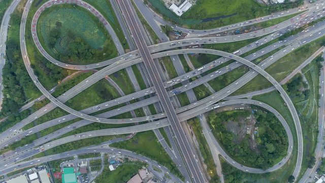 timelapse of night city traffic on 4-way stop street intersection circle roundabout in bangkok at day, thailand. 4K UHD horizontal aerial view.