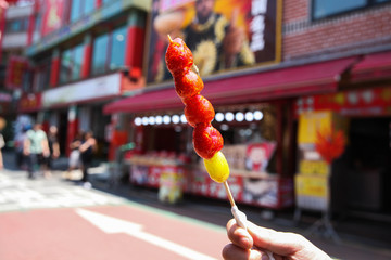 Hand holding a traditional Chinese snack, candied strawberries fruit skewers