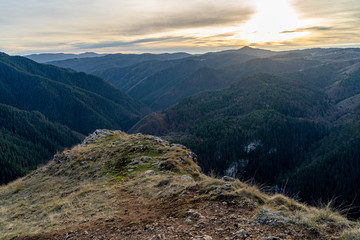 Naklejka premium Beautiful sunset in Rhodope mountains during the autumn with green trees in the hills and clouds in the sky