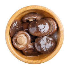 Marinated shiitake mushrooms in wooden bowl isolated on white. Top view.
