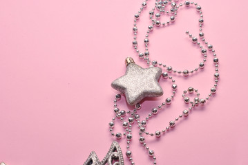 Shiny silver Christmas decoration beads and star on the pink paper background closeup top view macro. Sparkling beautiful background with free copy space place for text