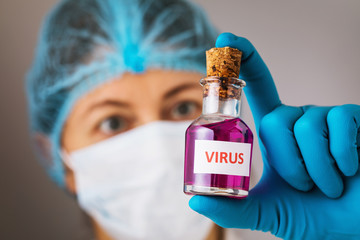 The doctor holds a bottle with a virus in his hands. Concept on the illegal manufacture of toxic...