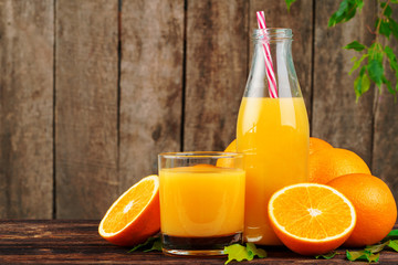 Fototapeta premium Bottle of orange juice with oranges on wooden table