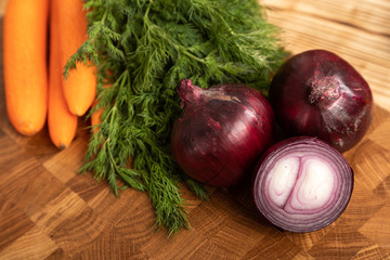 carrots and chilli peppers, greens on a wooden cutting board