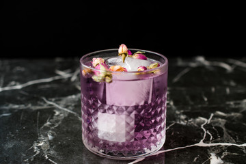 Pink Gin Tonic Cocktail with Dried Rose Buds and Ice in Glass Cup