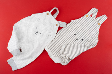 Baby clothes top view on red background