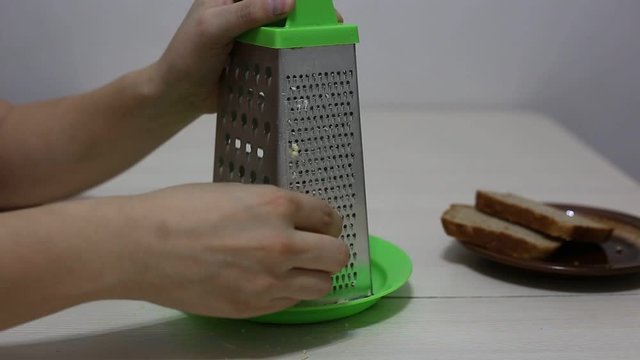 Hands grating cheese. Close-up footage.
