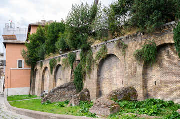 Fototapeta na wymiar Aurelian Walls. Ancient Roman fortress walls of Rome in sunlight. Overgrown stone urban walls with trees. Historical Italian landmark. Rome, Italy