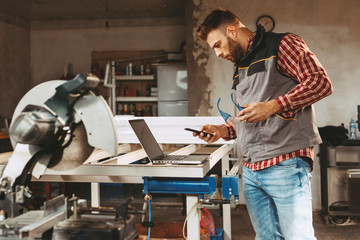 Young man work in home workshop using smartphone