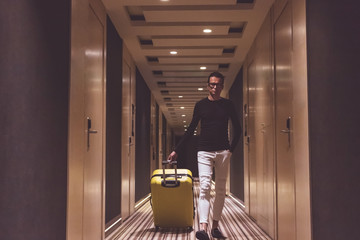 Man with suitcase walking in hotel lobby.