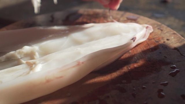 Old lady using knife for cut a squid in a half. handheld shot