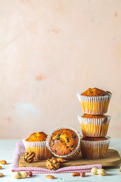 Vanilla caramel muffins in paper cups on white wooden background.