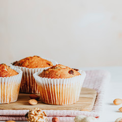 Vanilla caramel muffins in paper cups on white wooden background.