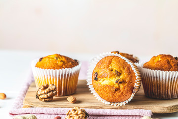 Vanilla caramel muffins in paper cups on white wooden background.