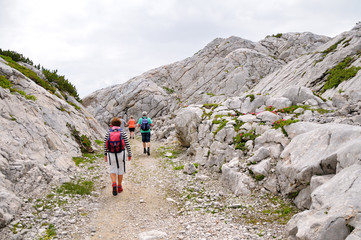 Fototapeta premium Elderly tourists hiking on a stone road in the mountains.