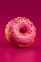 Yummy glazed round donut on a bright pink background