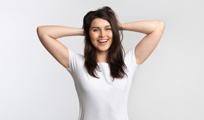Fototapeta premium Positive Girl Touching Hair Standing Posing Over White Background, Studio
