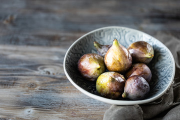 Fresh ripe figs in a bowl on a dark wooden table. selective focus. Copy space.