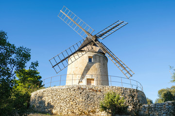 Plakat Joucas. Provence. France. October 05.2019. Editorial. Old windmill on a stone stand in the park under the evening sun.