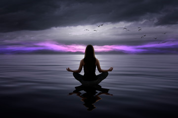 Beautiful woman doing yoga at the sea