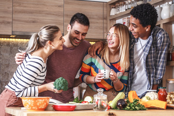 Group of friends preparing vegetarian meal.They preparing food and making fun in the  kitchen.