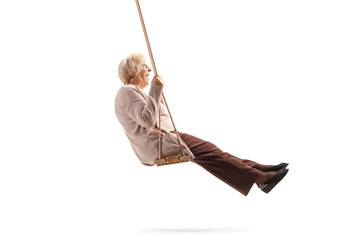 Elderly lady enjoying on a wooden swing - obrazy, fototapety, plakaty