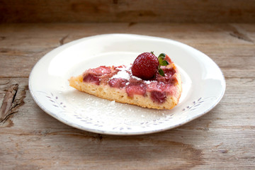 Round strawberry pie with fresh strawberries slice on white plate dish on wooden table background