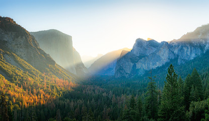 Beautiful panoramic sunrise at famous Tunnel View in scenic Yosemite Valley with El Capitan and Half Dome mountain summits in beautiful golden morning light, Yosemite National Park, California, USA