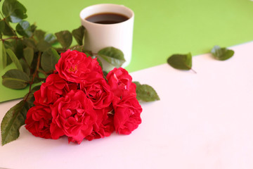 Hot coffe in awhite cup with natural red roses