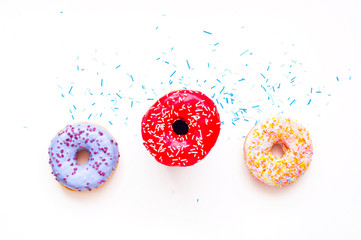 Colored donuts with colorful sprinkles on white background. Copy space