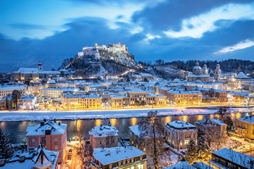 Classic aerial view of historic city of Salzburg with famous Festung Hohensalzburg and Salzach river illuminated in beautiful twilight at Christmas time in winter, Salzburger Land, Austria