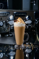 coffee in a glass with whipped cream, pieces of walnut and anise
