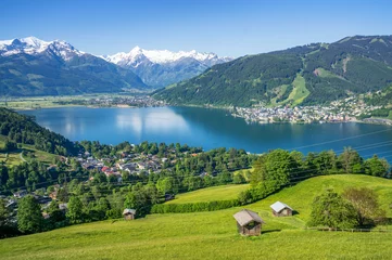 Selbstklebende Fototapete Natur Panoramablick auf die wunderschöne Landschaft in den Alpen mit klarem See, grüner Wiese, blühenden Blumen, traditionellen Almhütten an einem sonnigen Tag mit blauem Himmel im Frühling, Zell am See, Salzburger Land, Österreich