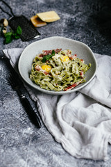 Green carbonara pasta with spinach in a gray plate on a turquoise background