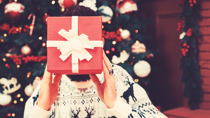 Handsome young man opening Christmas gift at home. Happy Christmas holidays. Happy New Year....