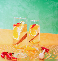 Drink with orange, chili, quince and honey on an orange-green background.	