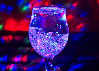 Glass with ice which reflects multicolored light.	