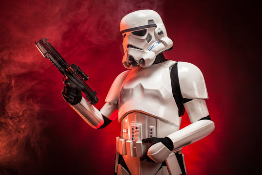 SAN BENEDETTO DEL TRONTO, ITALY. NOVEMBER 11, 2017. Studio portrait  of stormtrooper costume replica, with blaster E-11 gun. He is a fictional character of Star Wars saga. Red background with smoke