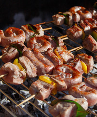 Meat and sausages skewers cooking on a grill