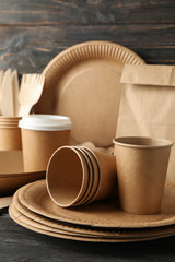 Eco - friendly tableware and paper bag on wooden table, space for text\