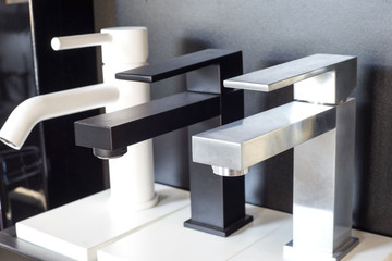 a variety of faucets taps on a white shelf in the store counter