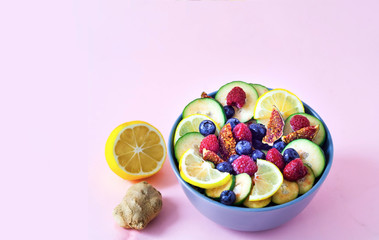 Fruit salad of wild berries and exotic fruits on pink background. The concept of a healthy diet, zero waste. Close up