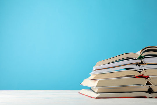 Stack of books against blue background, space for text