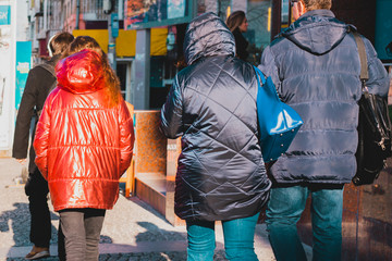 Adult daughter mother and father in jackets walks along the street in the city. Style. Cold. Outerwear. Winter. Back view