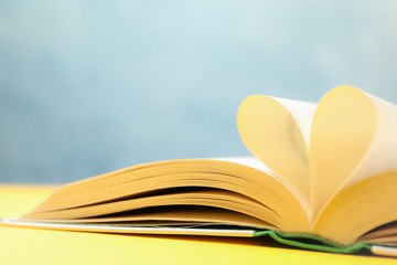 Heart made of pages. Book on yellow table, space for text