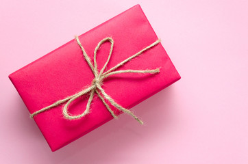 Pink gift box tied with twine on a light pink background. Holidays concept. DIY present idea. Flat lay. Copy space