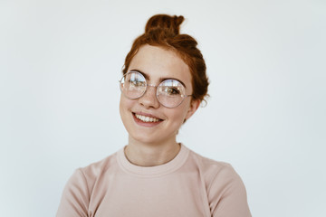 the girl in glasses for vision smiles a broad smile with beautiful teeth. gray background